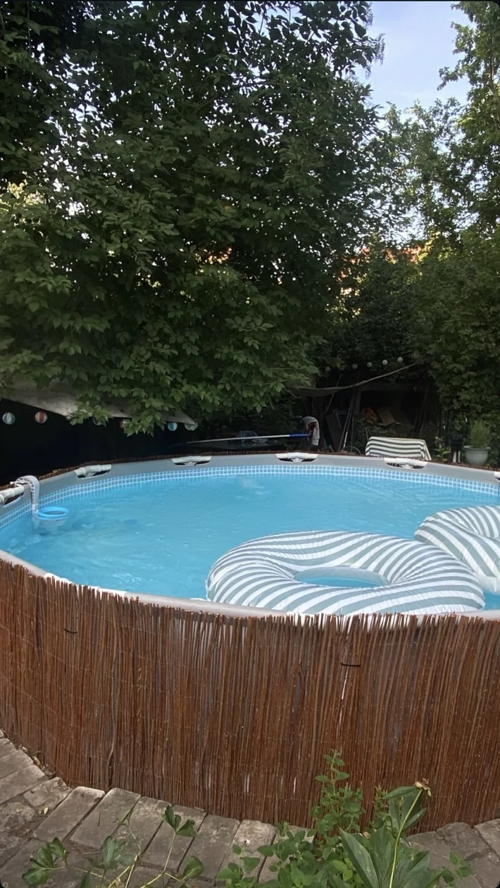 The round garden pool with turquoise water and striped inflatables